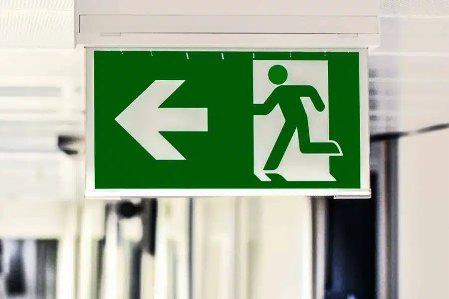 Green emergency exit sign with left arrow and running person icon