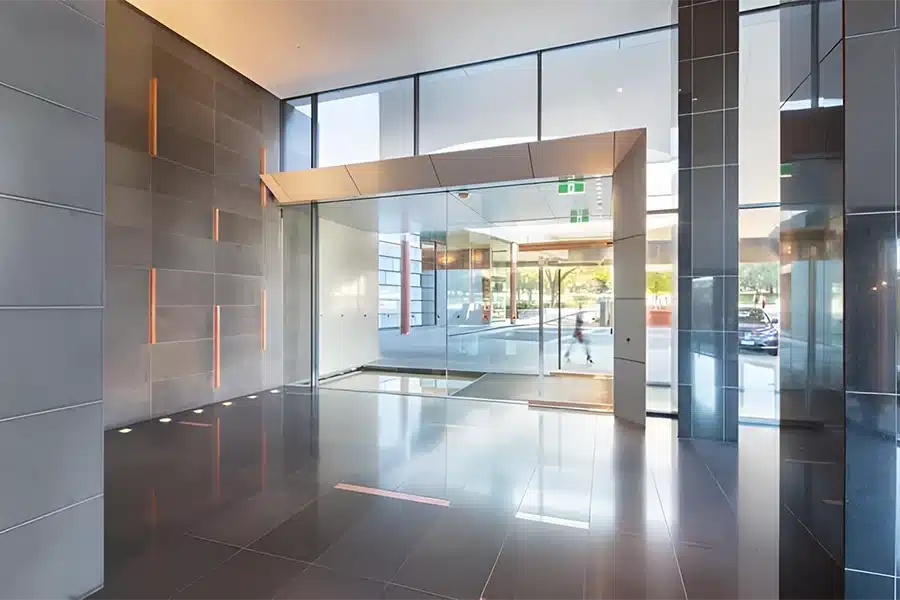 Empty office lobby with glass doors and polished black tile floors