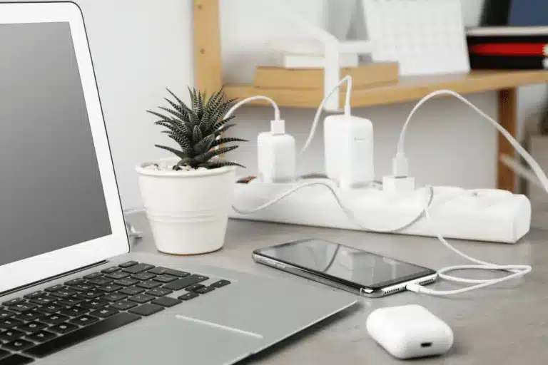 Modern workspace with a laptop, smartphone, and multiple chargers plugged into a power strip